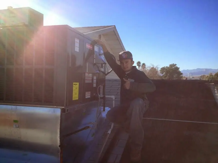 HVAC technician performing Heat Pump Repair on a rooftop unit in Roosevelt